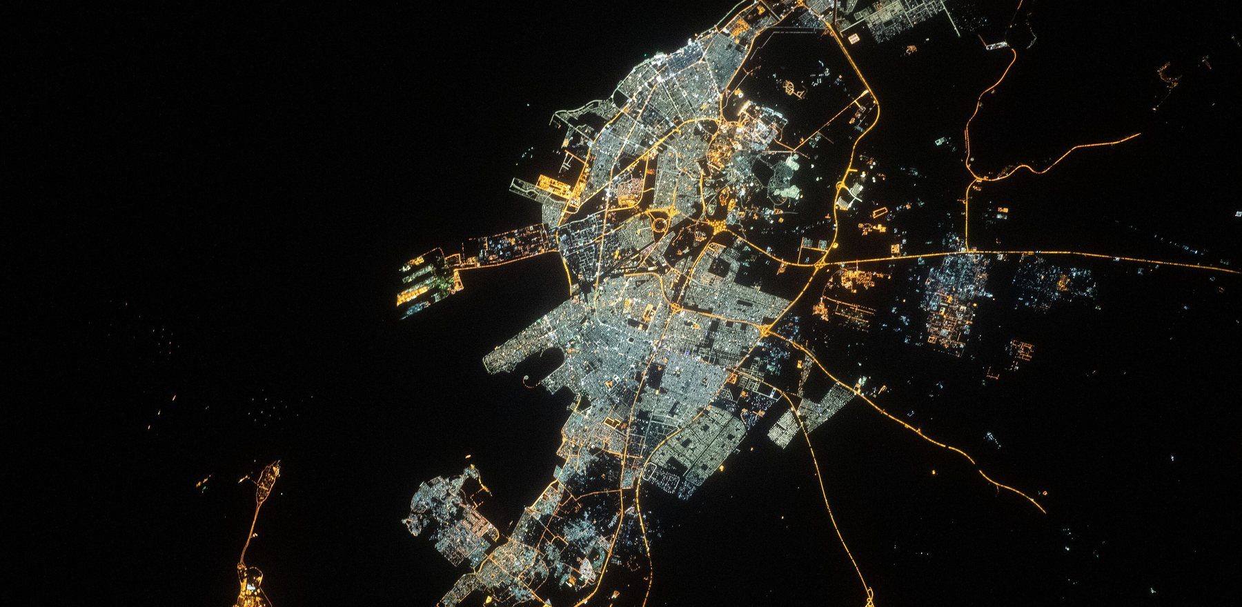 Night-time orbital photograph of a Saudi city, its road network visible as branching lines of light.