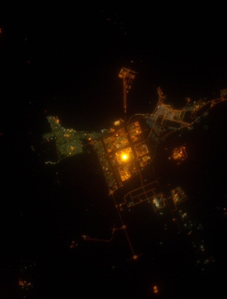 Night-time orbital view of an industrial Saudi coastal city lit in amber.